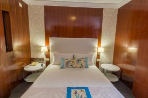 a bedroom with a large white bed with two tables at Hotel Eurosol Leiria & Jardim in Leiria