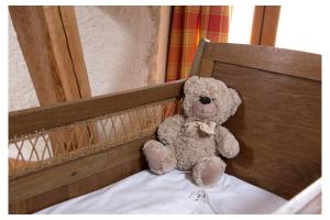a teddy bear sitting on top of a bed at Domaine de la Grange aux Dîmes in Feux