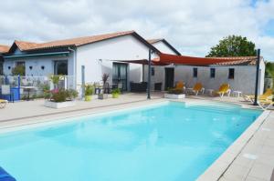 a swimming pool in front of a house at Les Jardins d'Oléron in Saint-Pierre-dʼOléron