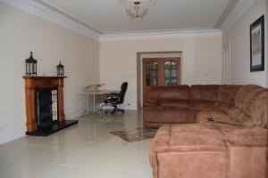 a living room with a brown leather couch and a desk at Amazing 4 Bed Scottish Baronial Style House in Westhill