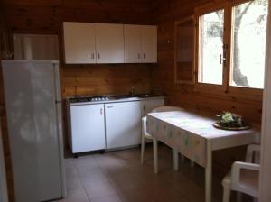 a kitchen with a white refrigerator and a table at VIOLA Club Village & Camping in Foce Varano