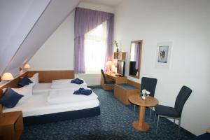 a hotel room with two beds and a desk at Hotel Am St. Georg in Leipzig