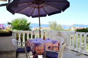 a table and chairs with an umbrella on a balcony at Apartments Stivic in Pinezici