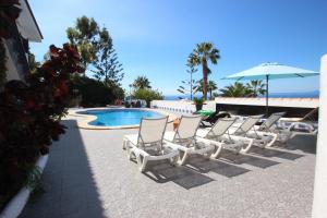 a group of chairs and an umbrella next to a pool at Casa Lodge Finca Alcalá in Alcalá