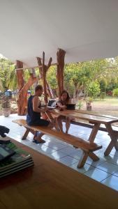 un hombre y una mujer sentados en una mesa de picnic con portátiles en Hostal y Restaurante Rancho Merida, en Mérida
