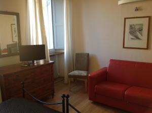 a living room with a red couch and a chair at San Francesco Bedrooms in Urbino