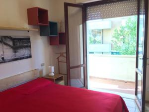una camera con un letto rosso e una grande finestra di Appartamento City Garden a Viareggio