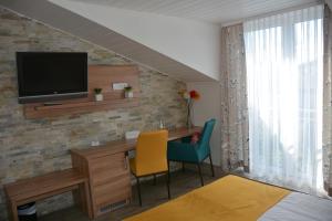 a room with a desk and a tv on a brick wall at Alpina Hotel in Rosenheim