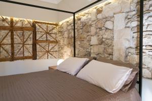 een bed in een kamer met een stenen muur bij Il Fuoco di Archimede - Ortigia in Siracusa