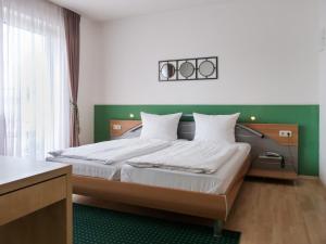 a bedroom with a large bed with a green headboard at City Hotel in Waldkraiburg