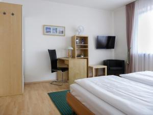 a hotel room with a bed and a desk and a television at City Hotel in Waldkraiburg