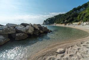a beach with a bunch of rocks and water at Rinaldi's Apartment in Sirolo +3 photos