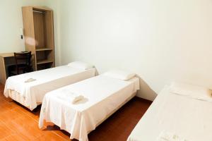 a room with two beds and a table and a chair at Hotel Oasis in Contagem