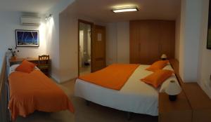 1 dormitorio con 2 camas con almohadas de color naranja en Enginyapartaments, en Figueres