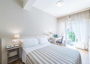 a bedroom with a bed and a desk and a window at Hotel Andreaneri in Marina di Pietrasanta +62 photos