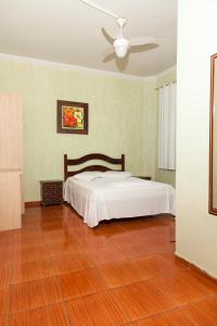 a bedroom with a bed and a ceiling fan at Hotel Oasis in Contagem