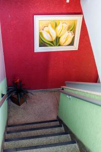 a painting of flowers on a red wall with stairs at Hotel Oasis in Contagem