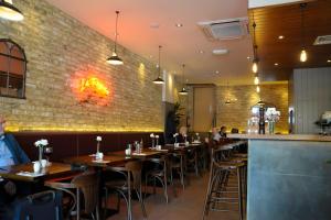 a restaurant with wooden tables and chairs and a brick wall at Kings Cross Inn Hotel in London