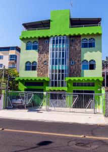 a green building on the side of a street at Hotel Oasis in Contagem