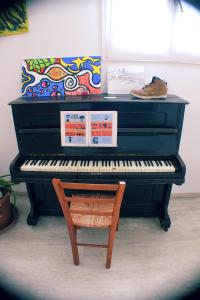 un pianoforte nero con una sedia di legno accanto di Ostello Bassano Del Grappa a Bassano del Grappa