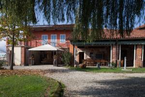 una casa de ladrillo rojo con una tienda blanca delante de ella en La Vigna Del Maestro en Bene Vagienna