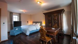 a bedroom with a bed and a desk and a television at Romantik Hotel Meisenheimer Hof in Meisenheim