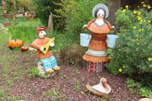 two scarecrow statues in a garden with pumpkins at Art Apartments in Midrakh ‘Oz