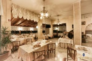 un ristorante con tavoli e sedie bianchi e un lampadario a braccio di Hotel Italia a Lerici