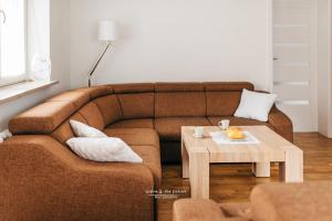 a living room with a brown couch and a coffee table at Apartament 3 - Bliżej Zdroju in Polanica-Zdrój