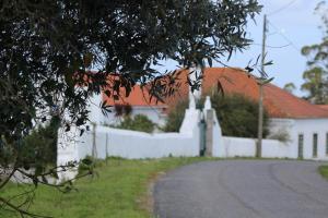 a white fence and a white house with a road at Casa da Quinta do Outeiro in Reveles