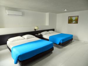 two beds in a hotel room with blue sheets at Hotel Don Gregorio in Cartago