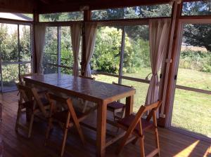 une table et des chaises dans une pièce avec fenêtres dans l'établissement Cabaña con costa de arroyo, à San Martín de los Andes