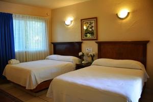 a hotel room with two beds and a window at Hotel La Hacienda in Tuxtla Gutiérrez