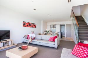 a man sitting on a couch in a living room at Doubtless Bay Villas in Cable Bay