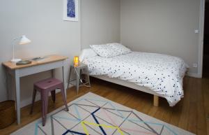 Habitación pequeña con cama y escritorio. en Chambre d'hôte parisienne en París