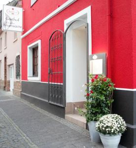 a red building with two potted plants on a street at Gasthof zur alten Feuerwache in Bad Hönningen