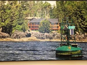 a boat in the water with a house in the background at Melfort Bell Guest Suites in Ucluelet