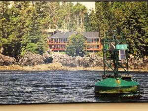 un barco en el agua con una casa en el fondo en Melfort Bell Guest Suites, en Ucluelet