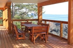 een houten tafel en stoelen op een veranda met uitzicht op de oceaan bij Melfort Bell Guest Suites in Ucluelet