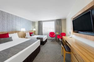 Habitación de hotel con 2 camas y TV de pantalla plana. en Hotel Diana en Brisbane