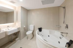 
a white bath tub sitting next to a white toilet at Best Western Plus Hotel Diana in Brisbane
