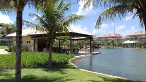a resort with a pond with palm trees and a building at apartamento vista mar in Aquiraz