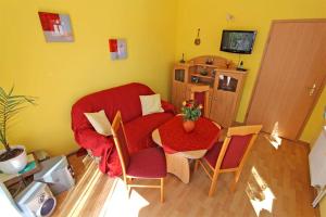 ein Wohnzimmer mit einem roten Stuhl und einem Tisch in der Unterkunft Ferienhaus Ribnitz MOST 751 in Ribnitz-Damgarten
