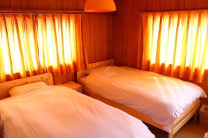 2 camas en una habitación pequeña con cortinas en Guest House Shimayado Aisunao, en Naoshima