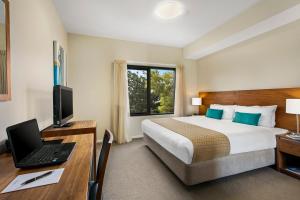 a hotel room with a bed and a desk with a laptop at Quest Bendigo Central in Bendigo