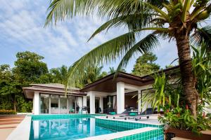een huis met een zwembad en een palmboom bij Baan Phukhao in Klong Muang Beach