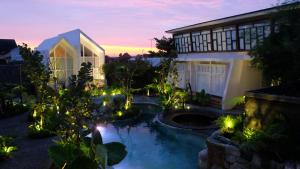 a backyard with a pond and a house with lights at YATS Colony in Yogyakarta