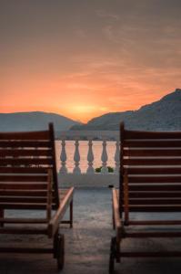 two benches sitting in front of a body of water at Anthi Maria Beach Apartments in Pefki