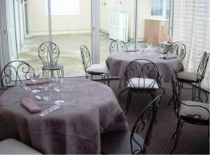 uma sala de jantar com duas mesas e cadeiras com mesa em L'Epicurien em Saint-Nicolas-de-Port
