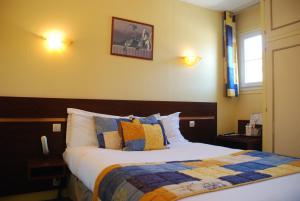 - une chambre avec un grand lit et des oreillers colorés dans l'établissement The Originals City, Hôtel Cathédrale, Lisieux (Inter-Hotel), à Lisieux
